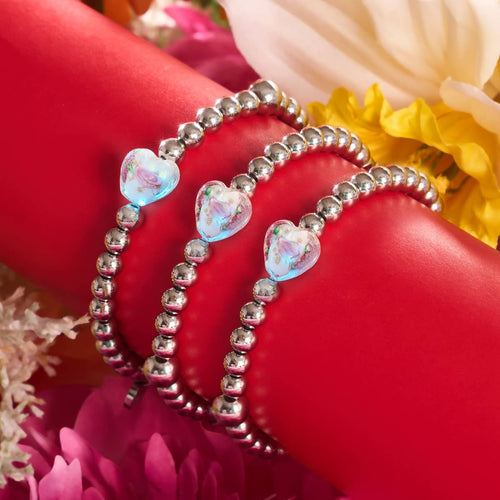 Magnolia glowing hearts essence bracelets with silver beads and glowing floral firefly glass hearts displayed on red stand with flowers by NOGU.